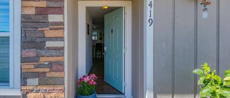 A house entrance with a stone wall, a blue door, and a number '5419' on the wall.