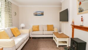 Ein Wohnzimmer mit einer Couch, einem Couchtisch, einem Fernseher und einem Kamin.
