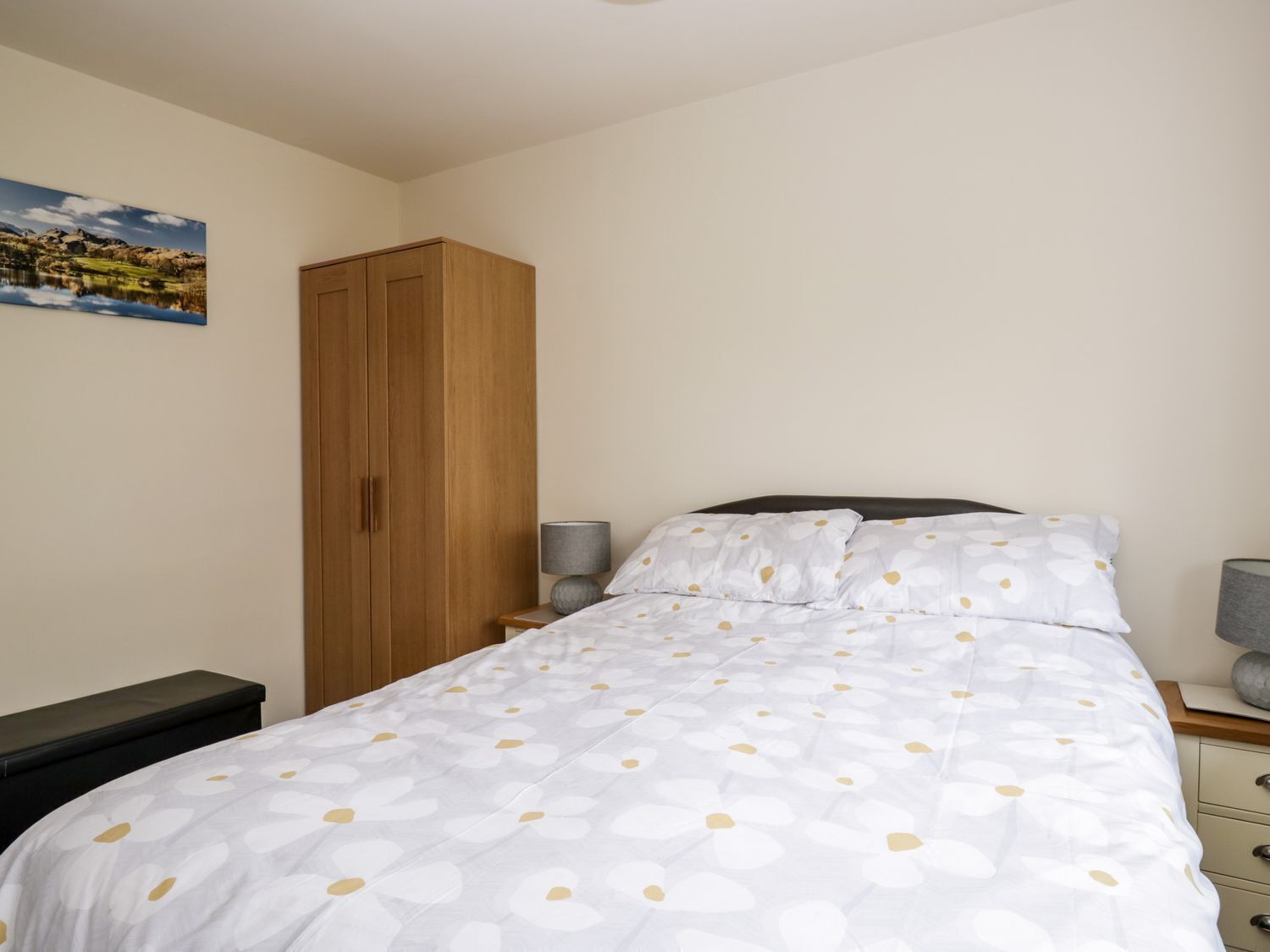 Une chambre à coucher avec un lit, une armoire, une table de chevet et une lampe.