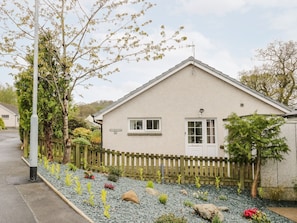 A single-story house with a white exterior, a small porch, and a wooden fence.