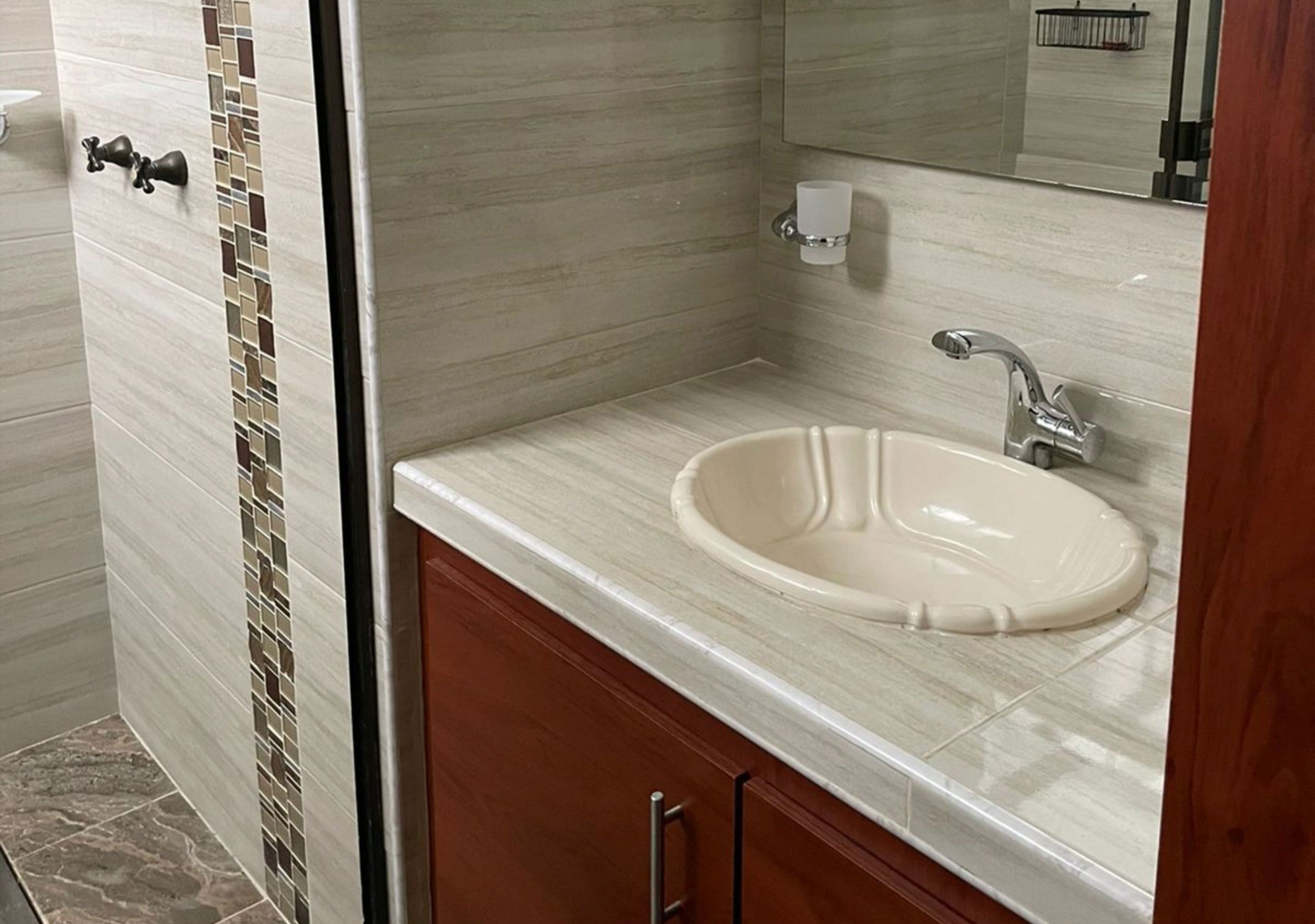 Un baño con lavamanos de mármol, un espejo y un perchero para toallas.