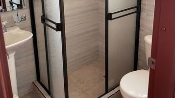 A bathroom with a glass-enclosed shower, a white sink, and a toilet.