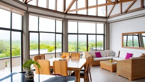 A spacious room with large windows, a dining area, and a seating area with a view of the outdoors. - Panorama Pueblo Tapao  (Montenegro)