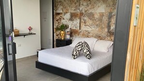 A modern bedroom with a bed, a nightstand, a wall-mounted air conditioner, and a textured wall. - Panorama Pueblo Tapao  (Montenegro)