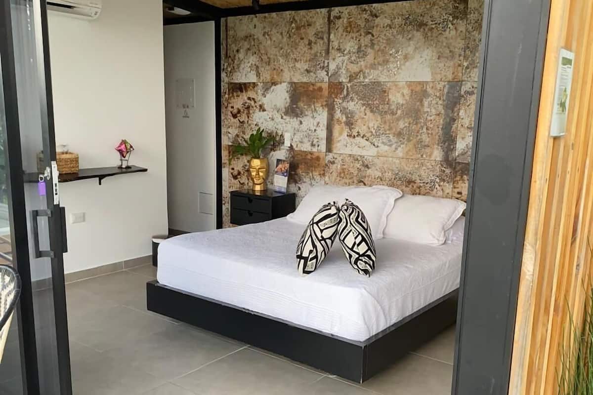 Ein modernes Schlafzimmer mit Bett, Nachttisch, Wandairconditioner und einer strukturierten Wand.