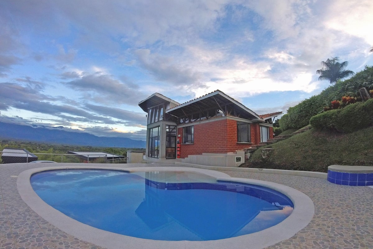 Ein modernes Haus mit Swimmingpool, einer gläsernen Veranda und Blick auf die Berge.
