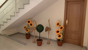 Un escalier menant à un palier où se trouve une porte en bois et un interrupteur fixé au mur.