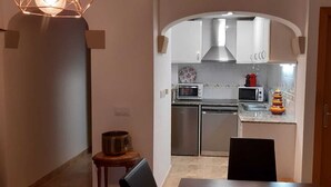 Une cuisine de taille réduite avec des meubles blancs, un four à micro-ondes, un grille-pain et un évier.