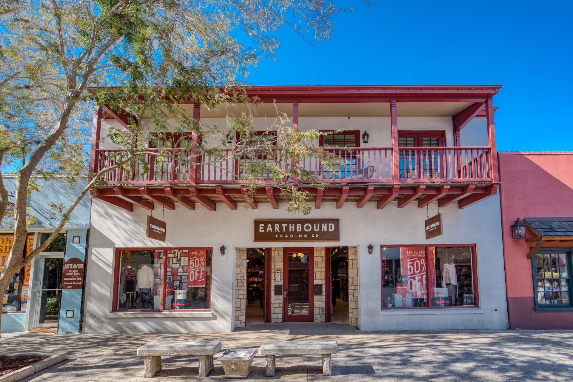 A two-story building with a balcony, storefronts on the ground floor, and a sign reading "EARTHBOUND TRADING CO."
