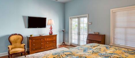 A bedroom with a bed, a dresser, a chair, a television, and a window with blinds.