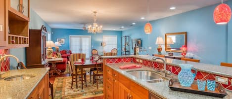A spacious kitchen with granite countertops, wooden cabinets, and a central island.