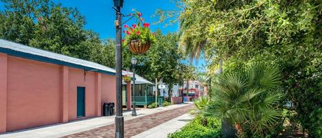 A street with a pink building, a black street lamp, and a hanging flower basket.