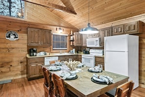 Enjoy meals and relaxation in this cabin's warm kitchen and dining area, featuring a large dining table and modern appliances.