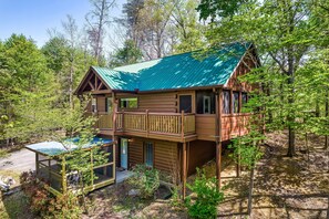 A two-story log cabin with a green metal roof, a balcony, and a glass enclosure. - Book Your 2026 Vacation!, Private!, Hot Tub, Great for Families, Sleeps 8! (Sevierville)