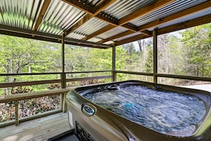Relax in a hot tub surrounded by a forest view.