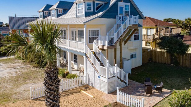 Une maison à deux étages avec un balcon, un escalier et une cour clôturée.
