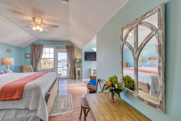 Une chambre d’hôtel avec deux lits, un ventilateur de plafond, une télévision et un grand miroir.