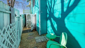 A narrow outdoor area with a turquoise fence, a white lattice gate, and a green chair. - Seaside Studio (St. Augustine)