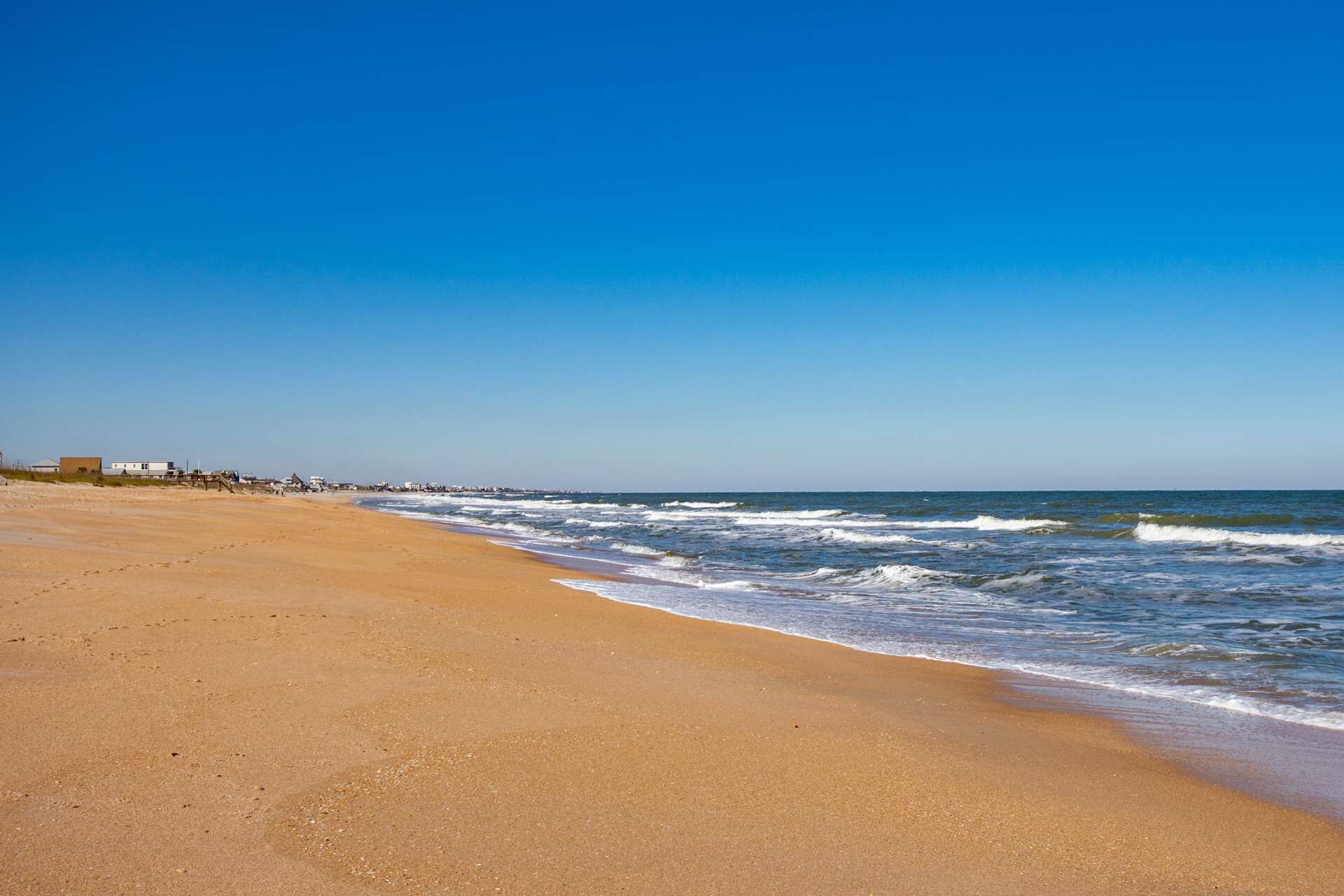 Uma praia com céu claro e mar calmo.