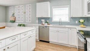 Une cuisine moderne avec des meubles blancs, un lave-vaisselle, un évier et une cuisinière.