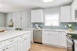 A modern kitchen with white cabinets, a dishwasher, a sink, and a stove. - Seascape Family Beach Retreat (St. Augustine)