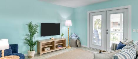 A living room with a TV, sofa, and a plant.