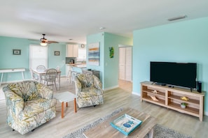Relax in a spacious living area with a large flat-screen TV, two armchairs, and a dining table.
