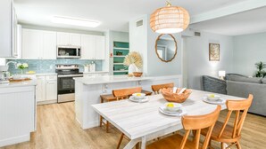 Une cuisine moderne avec des meubles blancs, un îlot central et un coin repas comprenant une table et des chaises.