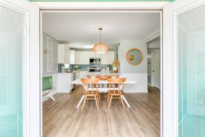 A modern kitchen with white cabinetry, a central island with seating, and a hanging light fixture. - Seascape 1 (St. Augustine)