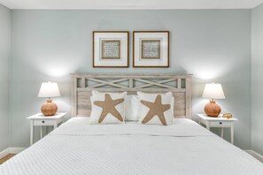 A bedroom with a bed, two nightstands, a headboard, and two framed pictures on the wall. - Seascape 1 (St. Augustine)