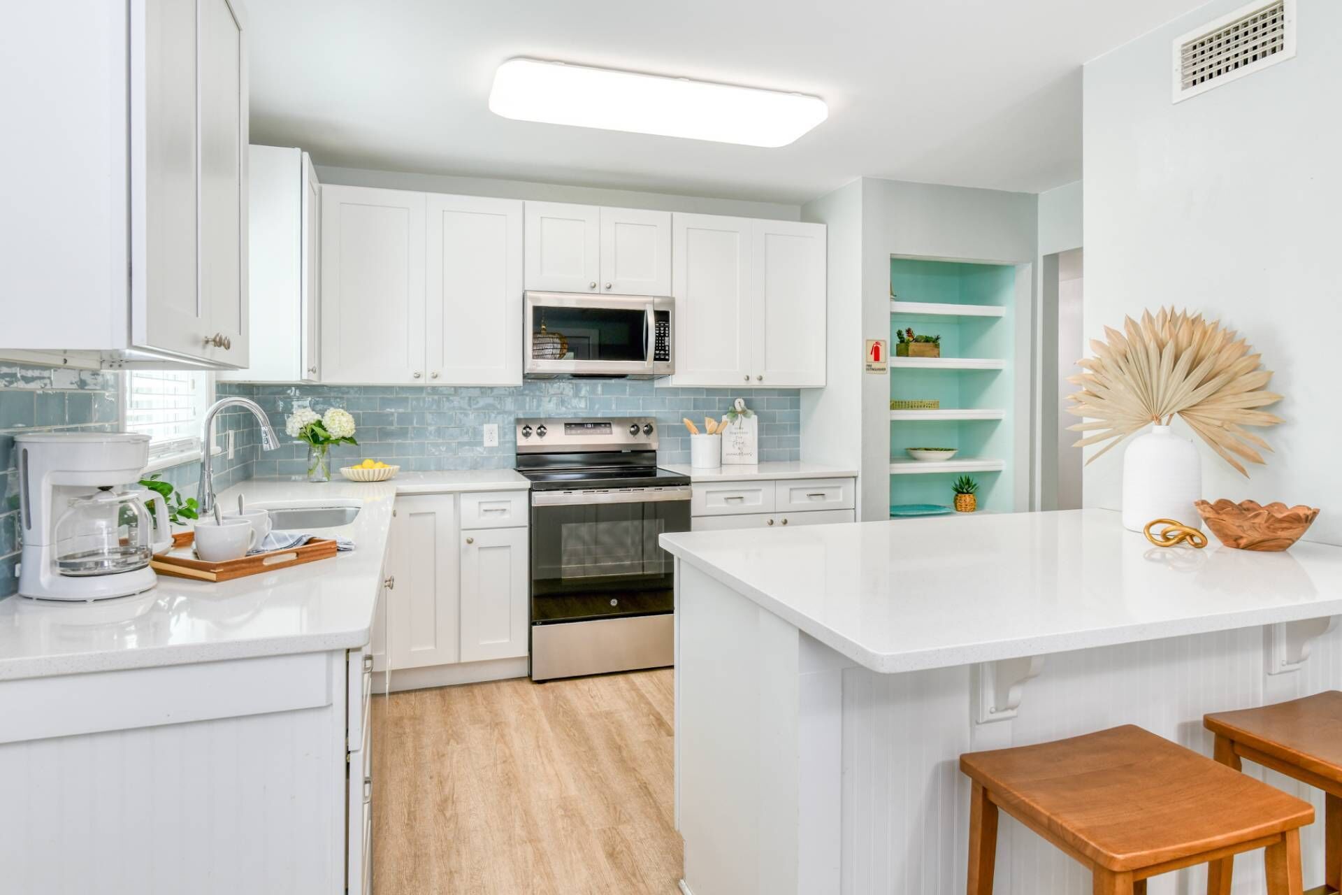 A modern kitchen with white cabinetry, a built-in microwave, and a coffee maker.