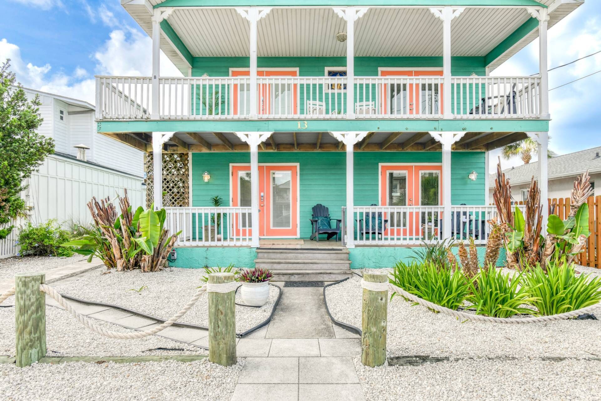 A two-story house with a balcony, a front porch, and a pathway leading to the entrance.