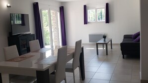 A spacious living area with a dining table, chairs, a sofa, and a TV. - 2 Bedroom Apartment in Anduze (Anduze)