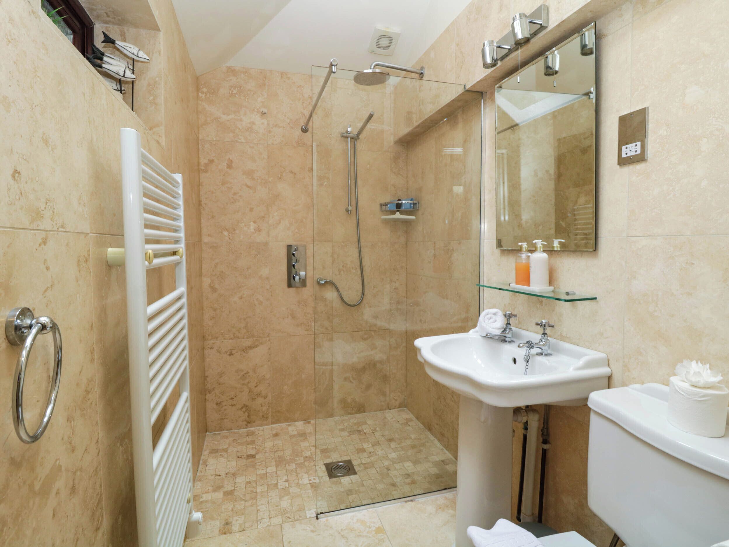 A modern bathroom with a glass shower enclosure, a white sink, and a toilet.