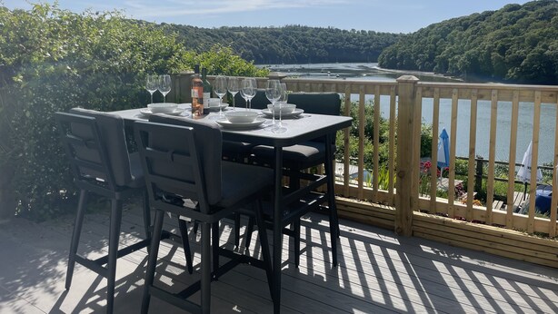 A table set for dining with a view of a lake and forest. - 4 Trenhaile Terrace (Truro)