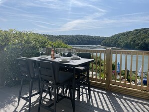 A table set for dining with a view of a lake and forest. - 4 Trenhaile Terrace (Truro)