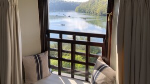 A room with a large window overlooking a lake with boats, surrounded by greenery. - 4 Trenhaile Terrace (Truro)