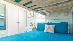 Ein Schlafzimmer mit einem Bett, einem Nachttisch, einer Lampe und einem gerahmten Bild an der Wand.