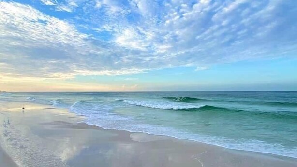 Ein Strand mit Wellen und blauem Himmel.