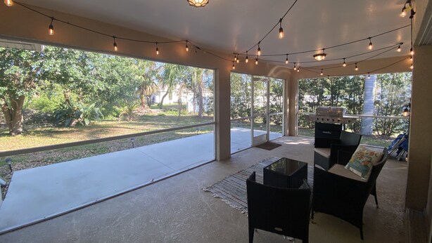 A covered patio with string lights, outdoor furniture, and a grill. - Cozy 3-Bedroom Home in North Port (North Port)