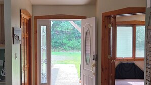 A spacious hallway with a patterned rug leading to a door with a glass panel, a wooden door, and a window with blinds. - The Good Place: Lakehouse Near Dunbar ATV Trails/On Blue Ox Trails (Fence)