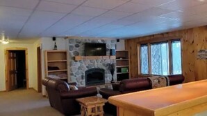 A cozy living room with a stone fireplace, leather sofas, and wooden shelves. - The Good Place: Lakehouse Near Dunbar ATV Trails/On Blue Ox Trails (Fence)