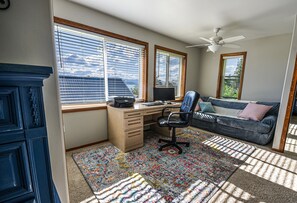 Ett rum med ett skrivbord, en stol, en soffa och en takfläkt.