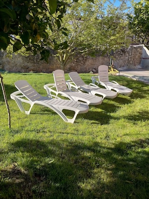 Outdoor lounge chairs arranged on a grassy lawn with a stone wall in the background. - Cozy apartment in Suances (Suances)