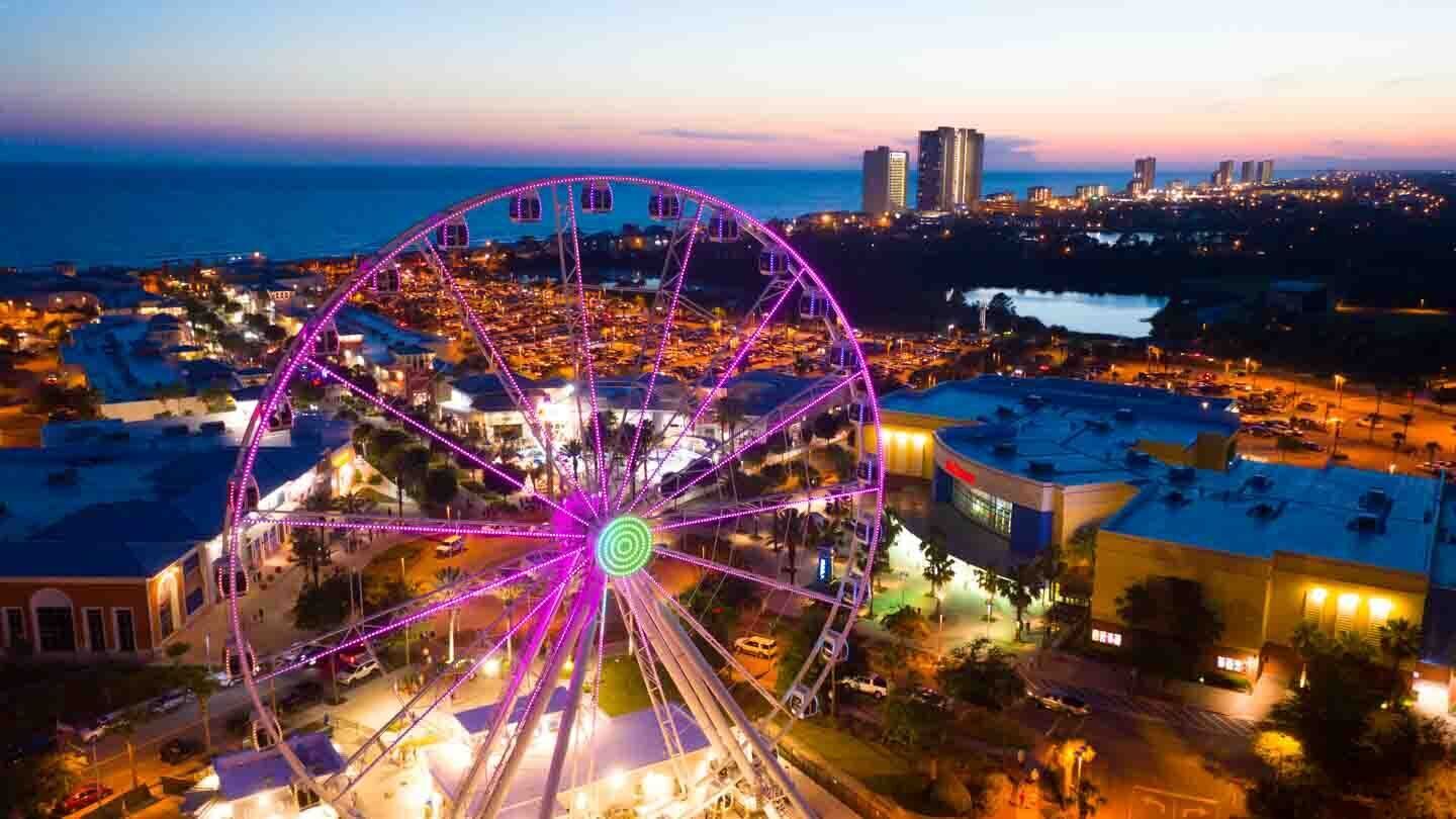 Une grande roue au crépuscule, avec une vue sur la ville en arrière-plan.
