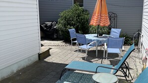 Un espace extérieur aménagé avec une table et des chaises, un parasol et un petit jardin.