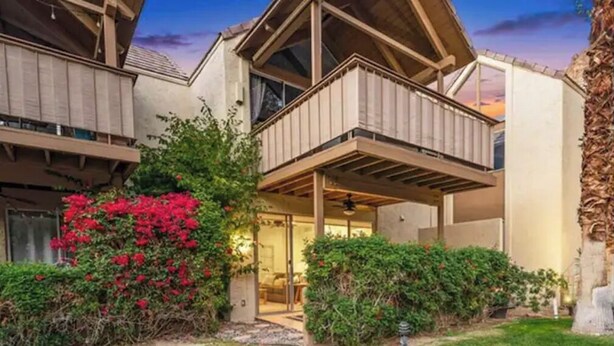 A modern two-story house with a balcony, surrounded by lush greenery and red flowers. - Sacred Cove Oasis - Indian Wells Tennis and Festival Hideaway (Indian Wells)