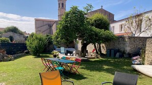 Un espace extérieur aménagé avec une table et des chaises, un mur en pierre et un arbre en arrière-plan.