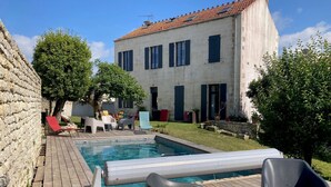Un espace piscine doté d’une terrasse en bois, de chaises longues et d’un mur en pierre.