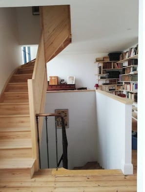 A wooden staircase leading to a lower level with a bookshelf on the right.
